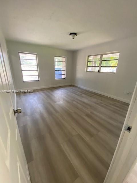 spare room with baseboards and wood finished floors