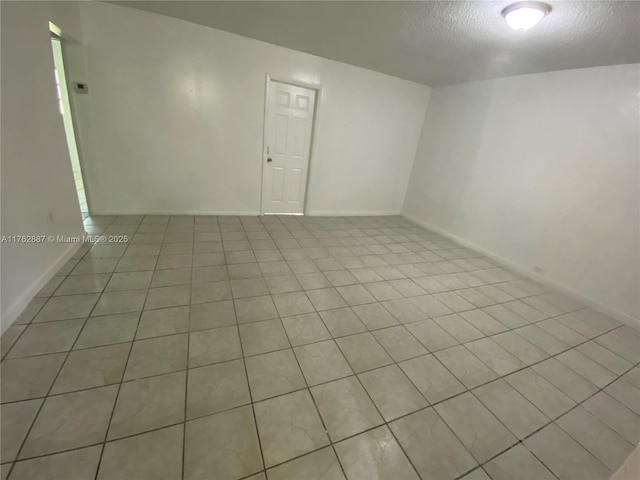 tiled spare room with baseboards and a textured ceiling