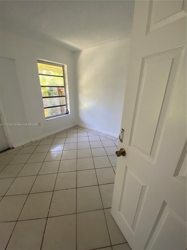 spare room with light tile patterned floors and baseboards