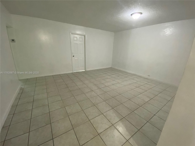 spare room featuring baseboards and a textured ceiling