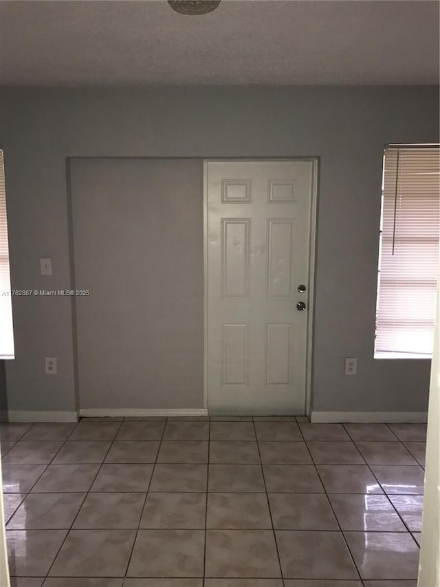 foyer featuring light tile patterned floors and baseboards