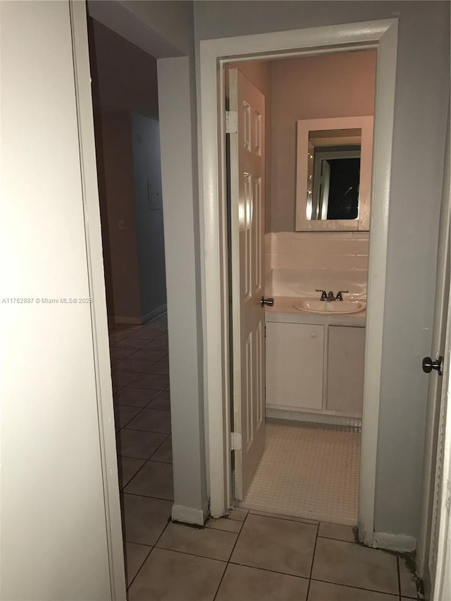 corridor with light tile patterned floors and a sink