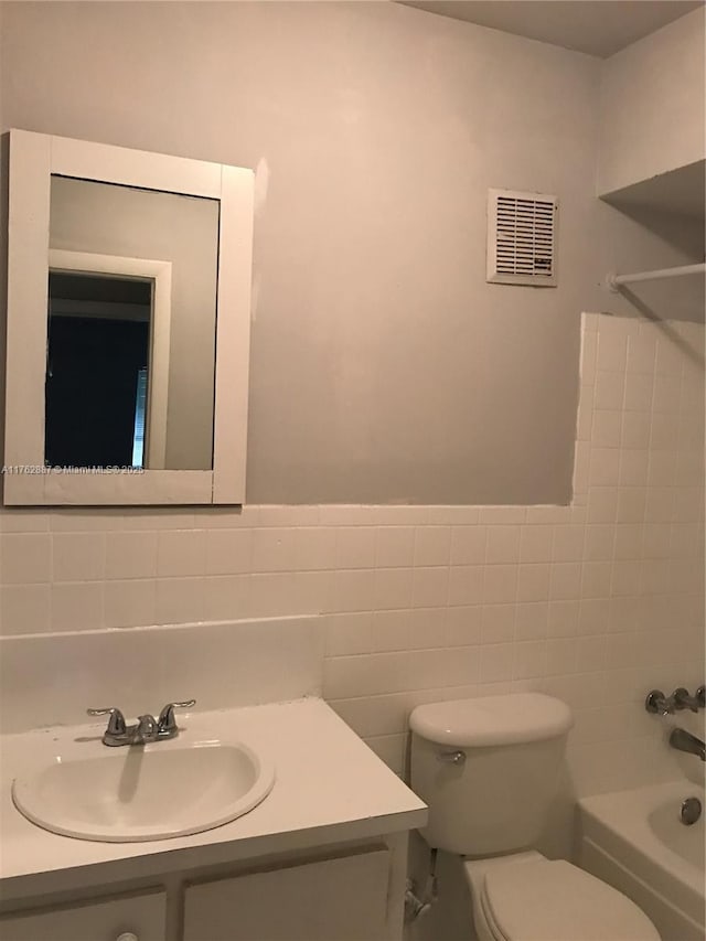 bathroom with visible vents, tile walls, toilet, shower / tub combination, and vanity