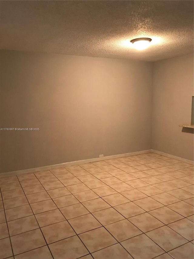 empty room featuring a textured ceiling and baseboards