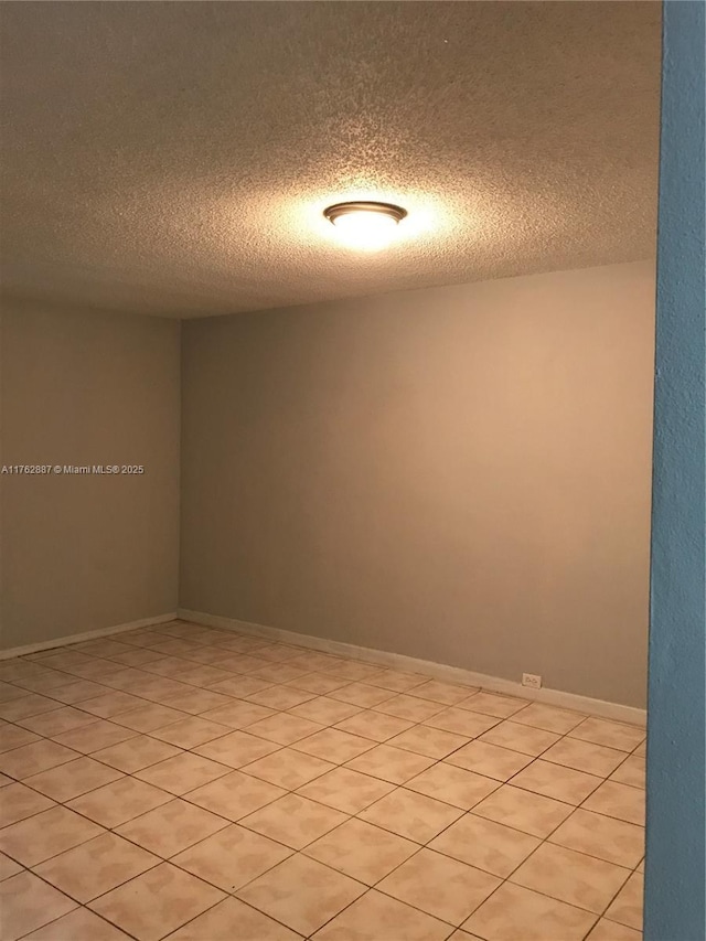 unfurnished room with baseboards and a textured ceiling