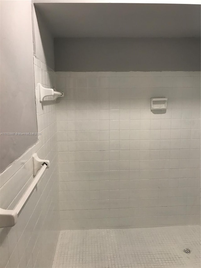 bathroom featuring a wainscoted wall and a tile shower