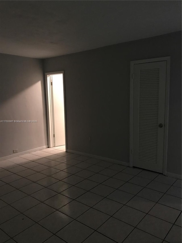 empty room featuring light tile patterned floors and baseboards