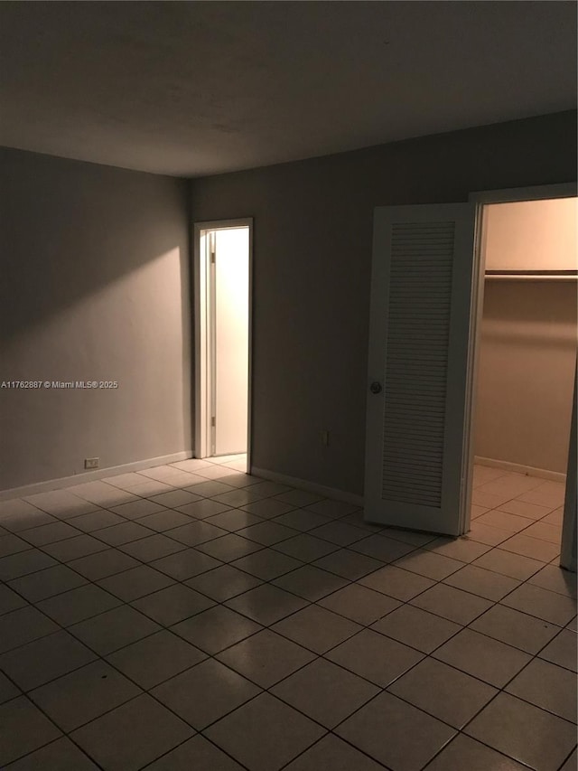 unfurnished room with light tile patterned floors and baseboards