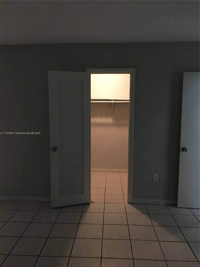 unfurnished room featuring light tile patterned floors and baseboards