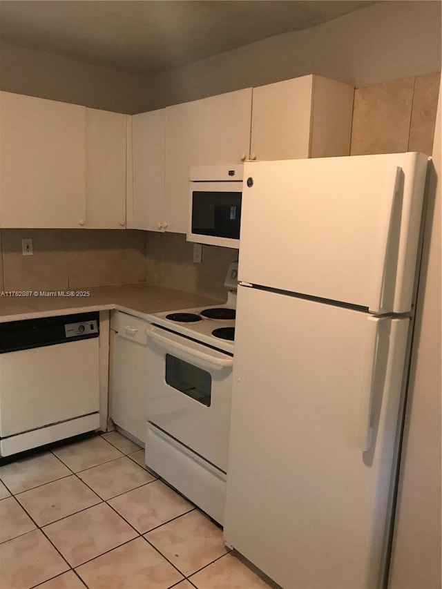 kitchen with light tile patterned floors, white appliances, and light countertops