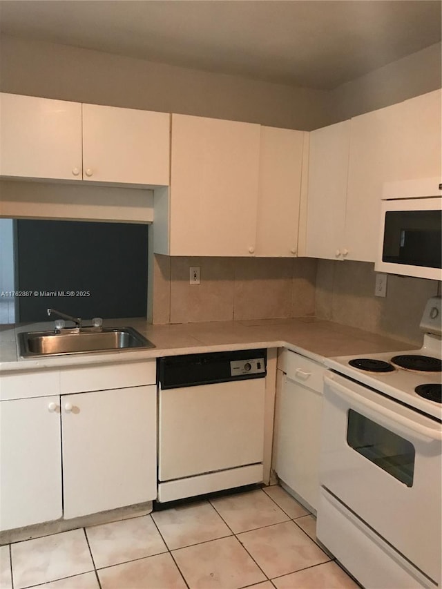 kitchen featuring white appliances, light tile patterned flooring, a sink, light countertops, and white cabinetry