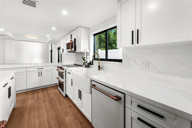 kitchen with visible vents, decorative backsplash, white appliances, white cabinetry, and a sink