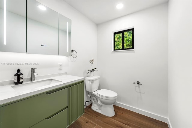 bathroom featuring toilet, wood finished floors, recessed lighting, baseboards, and vanity