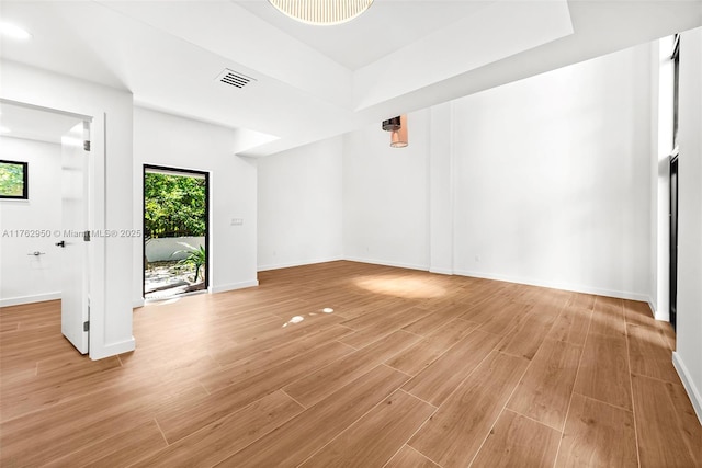 spare room with light wood finished floors, visible vents, plenty of natural light, and baseboards