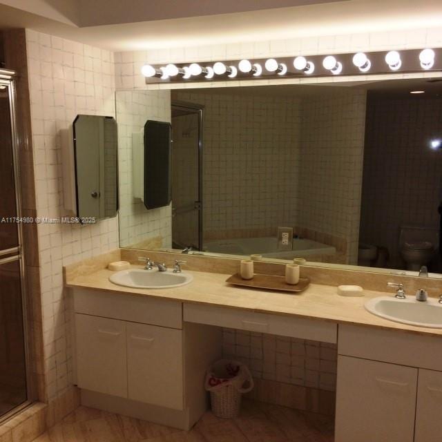 full bath with double vanity, tile walls, and a sink