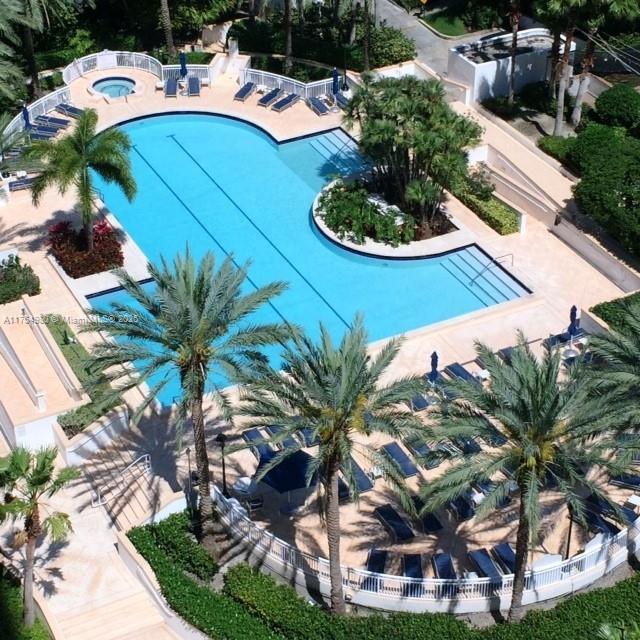 community pool with a patio area, fence, and a hot tub