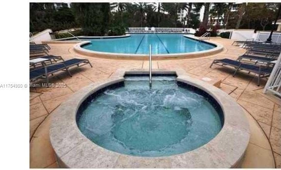 pool with a patio and a hot tub