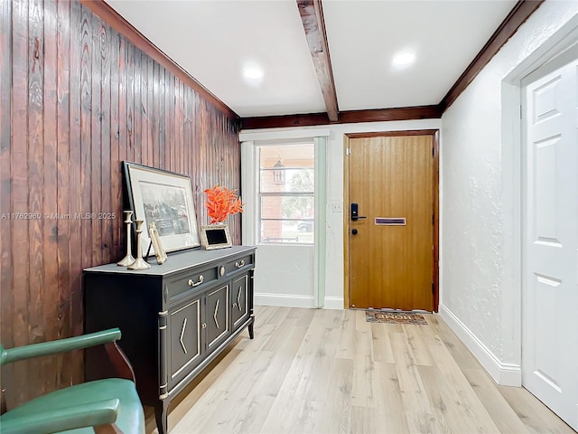 foyer entrance featuring beamed ceiling, light wood-style flooring, baseboards, and a textured wall