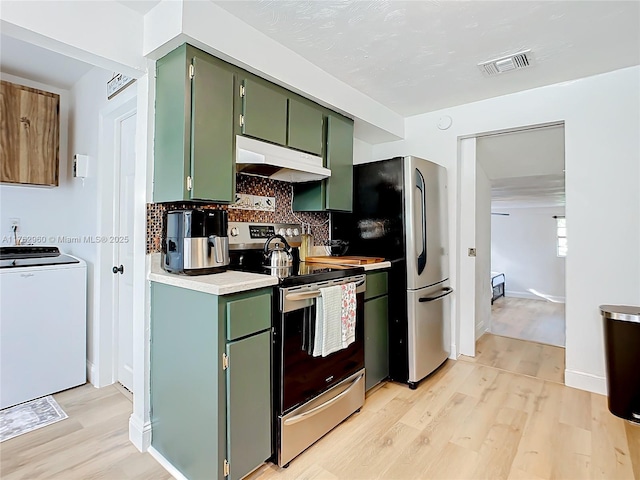 kitchen with under cabinet range hood, stainless steel appliances, green cabinets, light wood finished floors, and washer / dryer