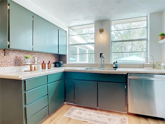 kitchen with a sink, light wood-style flooring, light countertops, and stainless steel dishwasher