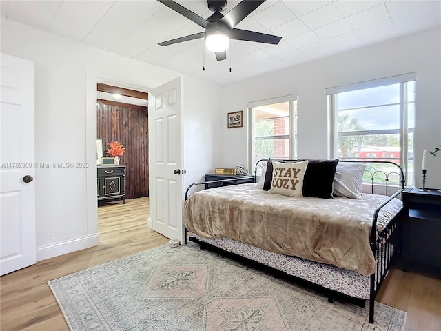 bedroom featuring light wood-style floors, baseboards, and ceiling fan