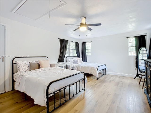 bedroom featuring light wood finished floors, multiple windows, attic access, and baseboards