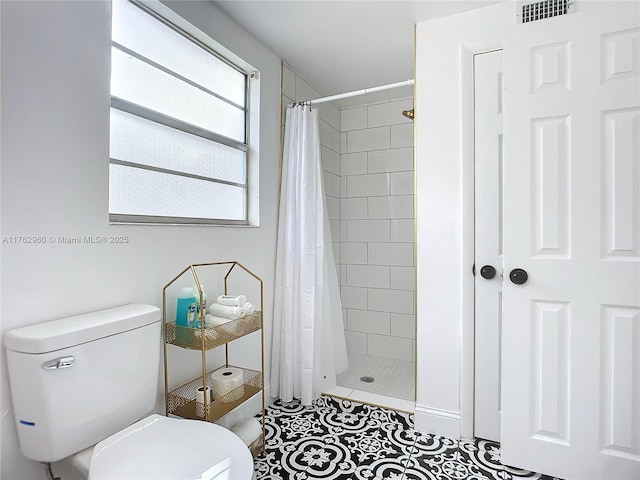 full bath with tile patterned flooring, toilet, visible vents, and a tile shower