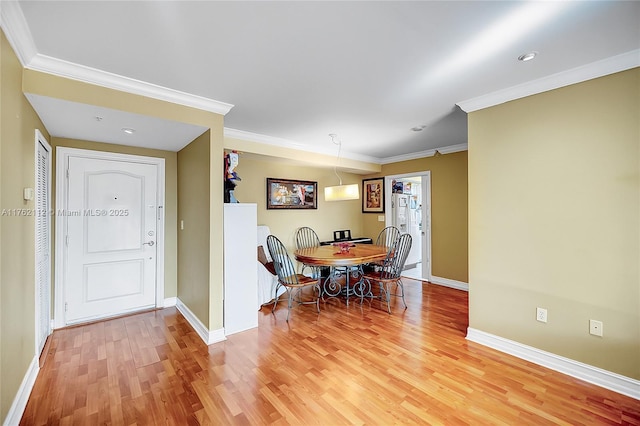 dining room with crown molding, light wood-style flooring, and baseboards