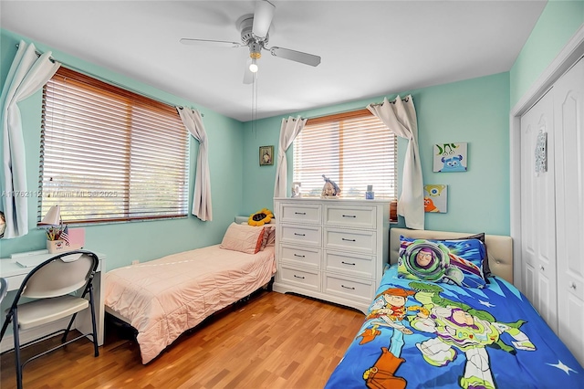 bedroom with light wood-style flooring, a ceiling fan, and a closet