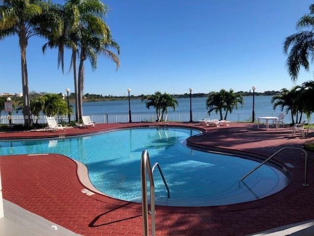 pool featuring a patio area and a water view