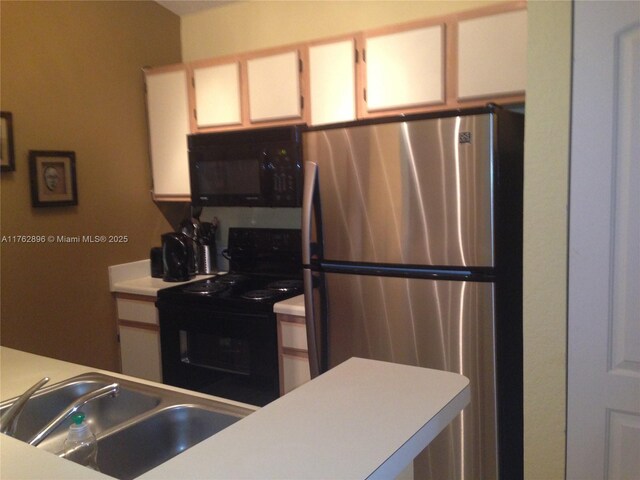 kitchen with black appliances, a sink, light countertops, and white cabinetry