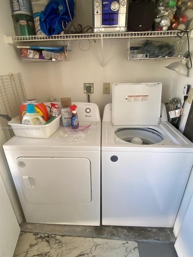 washroom featuring marble finish floor, washing machine and dryer, and laundry area