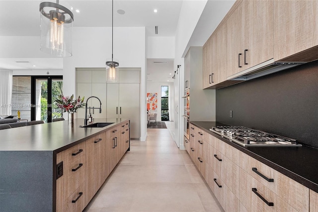 kitchen featuring modern cabinets, stainless steel gas stovetop, light brown cabinets, and a sink