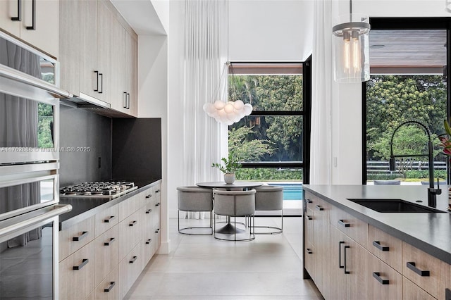 kitchen featuring a sink, stainless steel gas stovetop, a wealth of natural light, and light brown cabinets