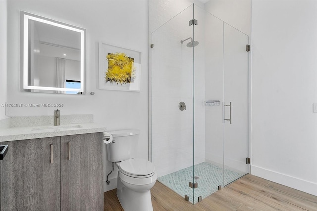 full bathroom with a shower stall, baseboards, toilet, wood finished floors, and vanity