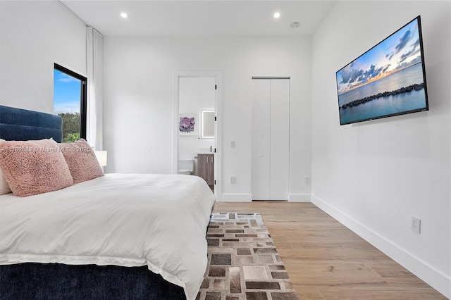 bedroom with light wood-style flooring, recessed lighting, baseboards, and connected bathroom