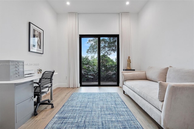 office space with recessed lighting, baseboards, light wood finished floors, and built in desk