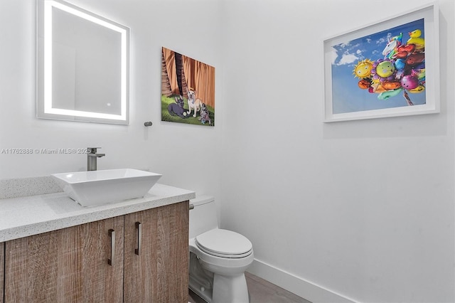 bathroom with toilet, vanity, and baseboards