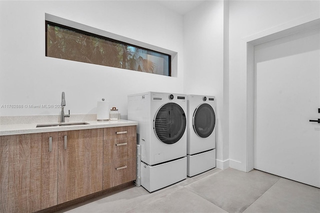 clothes washing area with a sink, cabinet space, and washer and dryer