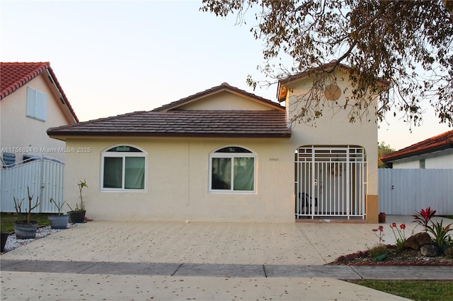 view of property exterior featuring a tiled roof, a gate, fence, and stucco siding