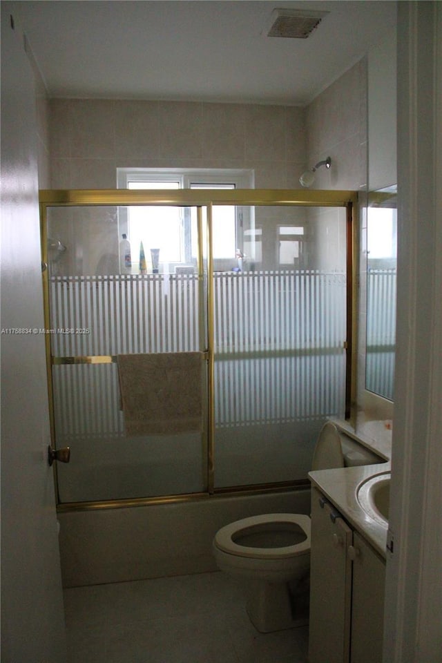 bathroom featuring visible vents, bath / shower combo with glass door, toilet, tile patterned floors, and vanity