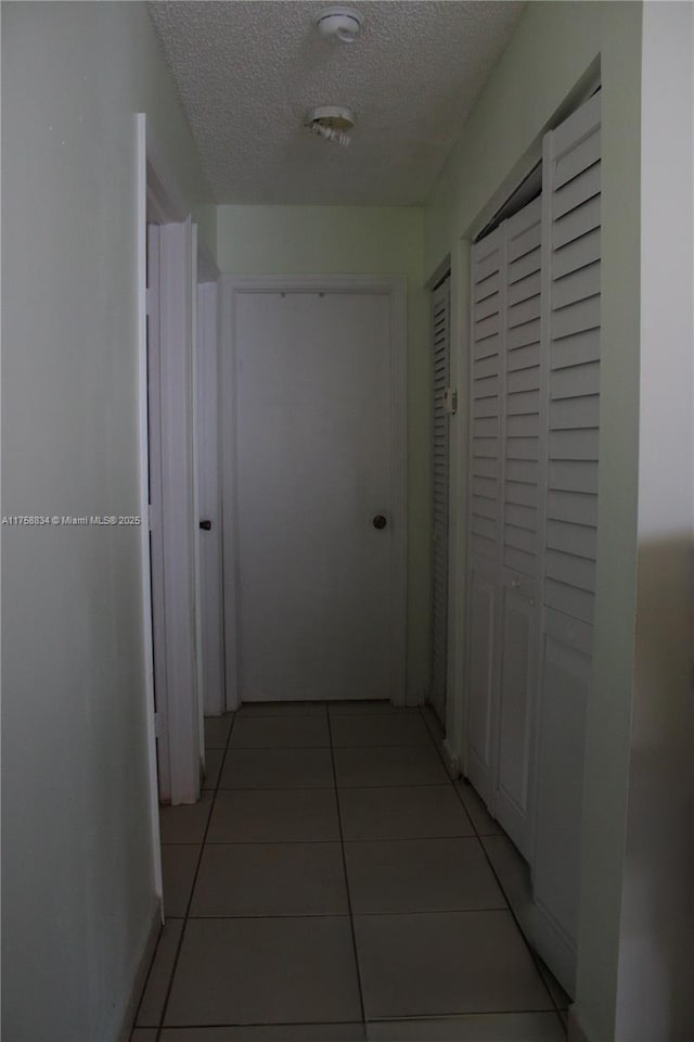 hallway featuring light tile patterned floors and a textured ceiling