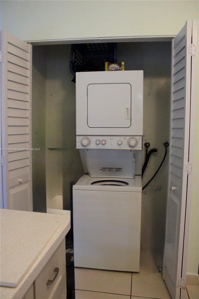 washroom with stacked washer and clothes dryer, light tile patterned flooring, and laundry area