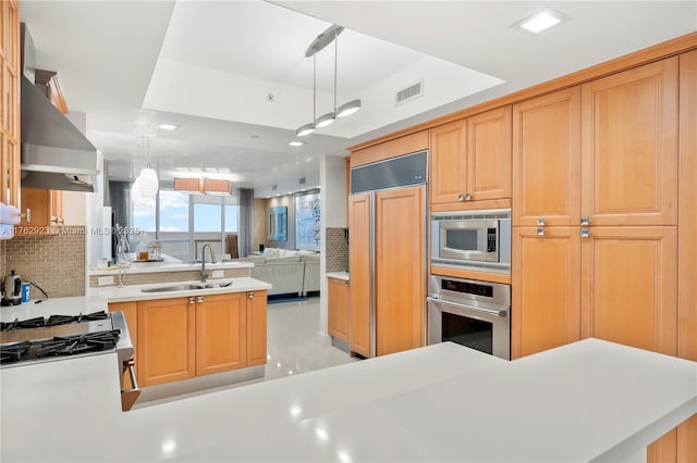 kitchen with visible vents, a sink, a tray ceiling, decorative backsplash, and built in appliances