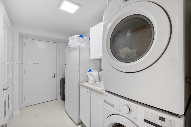 laundry room featuring light tile patterned floors, cabinet space, and stacked washing maching and dryer