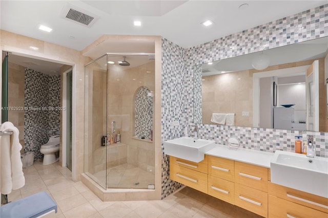 bathroom featuring visible vents, a stall shower, tile walls, and a sink