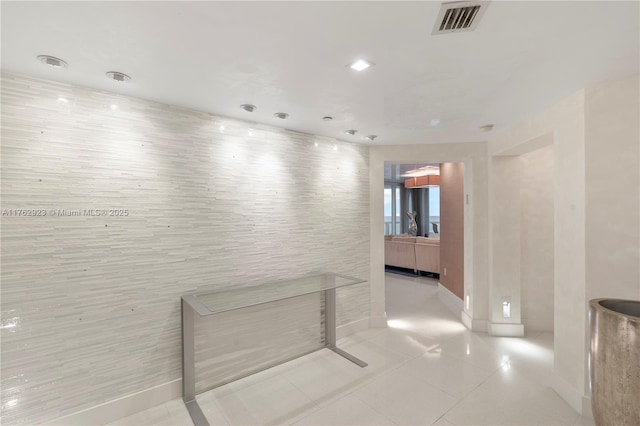 hall featuring tile patterned flooring, tile walls, and visible vents