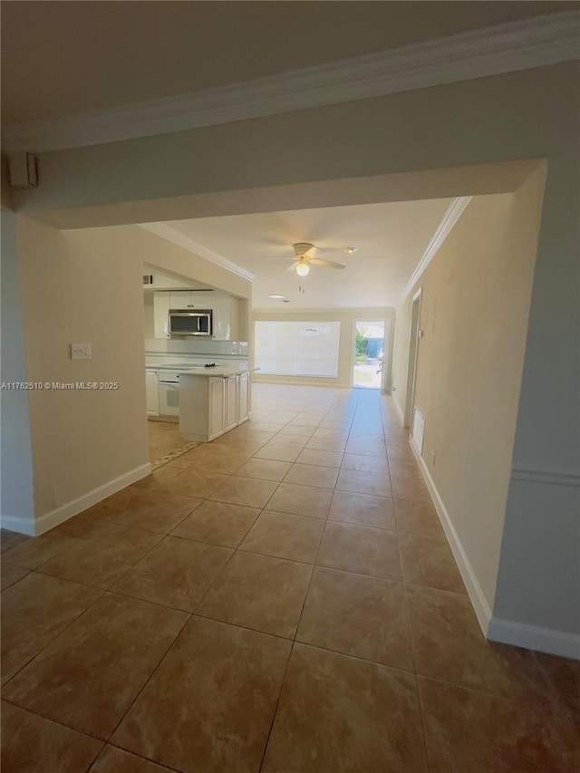 hallway with baseboards, ornamental molding, and light tile patterned flooring