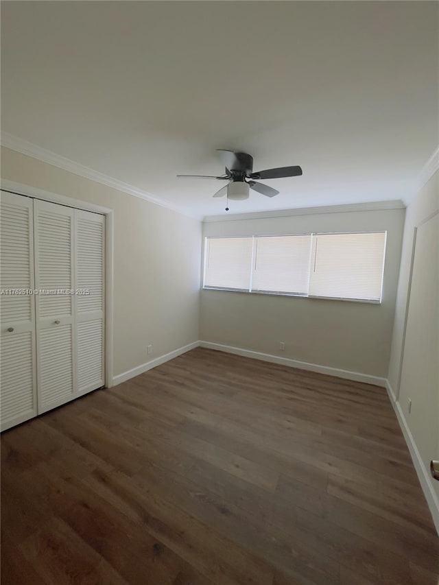 unfurnished bedroom with ornamental molding, a ceiling fan, wood finished floors, a closet, and baseboards