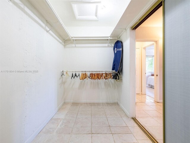 spacious closet with light tile patterned floors and attic access